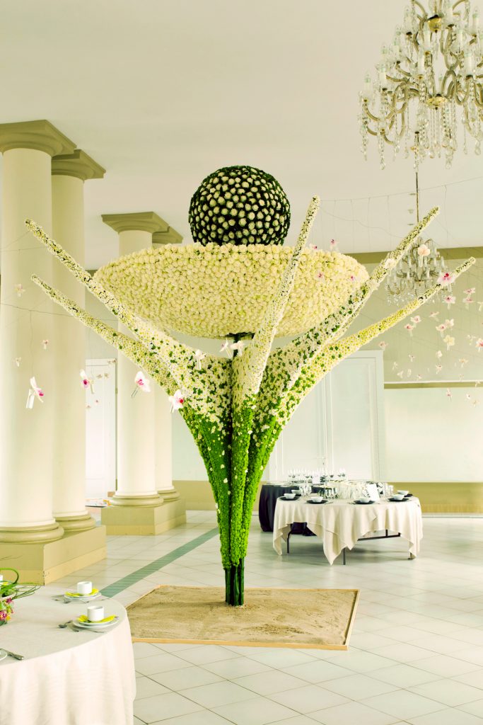 An enormous white roses ball is hanging in a white roses dish 3m above the ground and is supported towards the floor with a construction filled with green and white Chrysanthemum. Expo Bloom in Ostend Belgium opened by the Belgium King and Queen.
