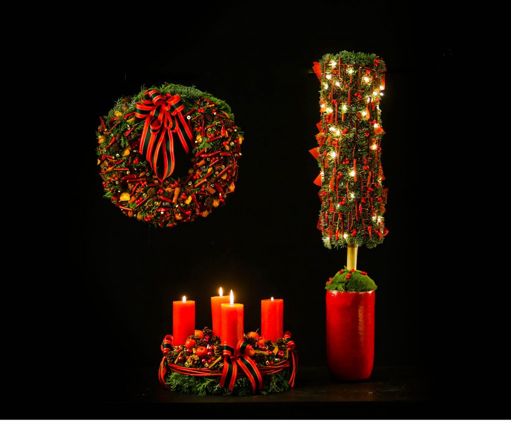 Typical Christmas decorations. A hanging wreath an alternative Christmas tree and a classic wreath with 4 candles on top. All created in a classic red-green setting.