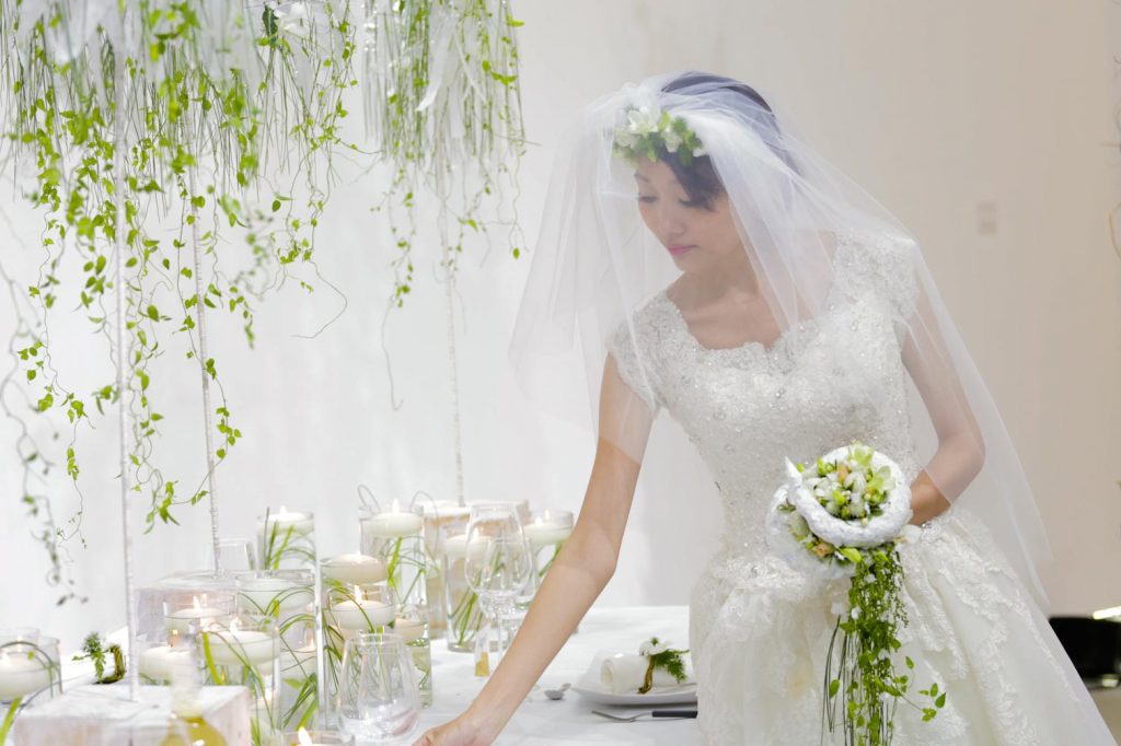In the program of the EFDE bridalwork is very important. A romantic bride with a veil and a beautiful round bridal bouquet in her hand inspects the table decoration of her wedding feast